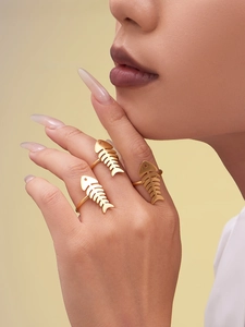 Close-up of three gold-plated stainless steel rings with a unique fishbone cut-out design
