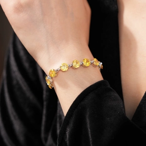 Macro view of round yellow gemstones on a silver chain bracelet worn over black velvet