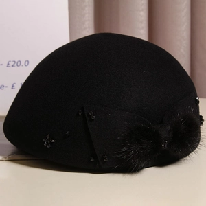 Close-up of black wool beret featuring elegant rhinestone bow and soft mink fur pom-pom