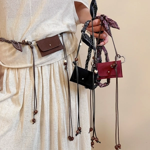 Detail of vintage fabric and wood bead mini bag charms shown as stylish belt accessories