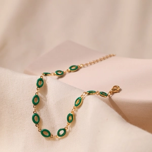 Detail of vintage gold bracelet featuring green enamel ovals and adjustable lobster clasp