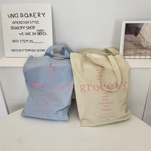 Détail du sac cabas en toile avec liste florale imprimée et lettrage grocery aux tons doux