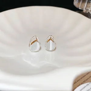 Elegant silver teardrop cat-eye stone earrings displayed on a minimalist white wavy tray