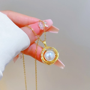 Rotating bird nest pendant necklace with pearl and crystals on gold chain