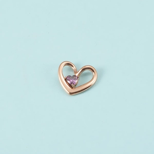 Détail du pendentif cœur en or rose avec pierre précieuse violette sur fond bleu clair