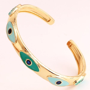Detail view of gold-plated open cuff bracelet with blue and green evil eye enamel motifs