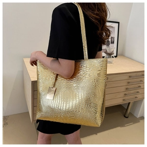 Detailed close-up of a large gold tote bag with crocodile pattern in a lifestyle setting