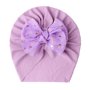 Close-up of light purple ribbed knit baby turban hat with a gold polka dot tulle bow