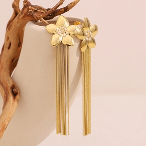 Macro detail of 18K gold-plated flower earrings with delicate tassels and pearl accents