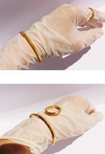 Detail of gold-plated ribbed texture snake-bone bracelet and open ring set on purple background