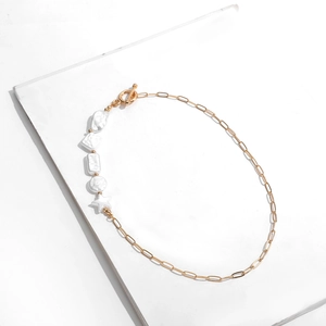Detailed close-up of mixed geometric charms and gold chain links on a beaded necklace