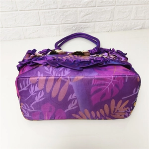 Detail of a large purple floral tote bag with leaf patterns and handmade 3D flowers