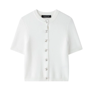 Detailed macro view of white knit cardigan featuring shiny silver bow-shaped button closures