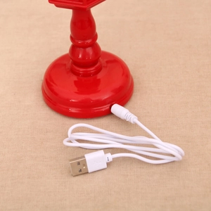 Detail of red Christmas lantern base with white USB to DC power cable on fabric