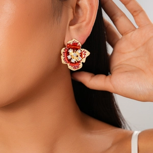 Close-up of a vintage red floral earring with gold trim and sparkling rhinestones