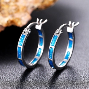 Dettaglio macro di orecchini a cerchio geometrici argento con intarsi blu glitterati