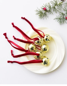 Detail of six gold metal bells with red velvet ribbons and pine branch decorations