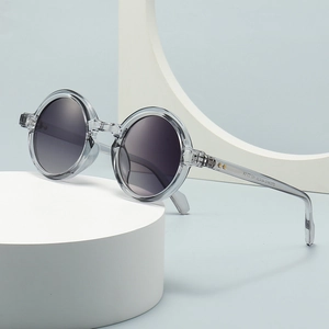 Retro round grey transparent frame sunglasses with gradient lenses in minimalist studio setting