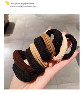 Close-up of five thick elastic hair ties in black, coffee, and beige colors on a hand