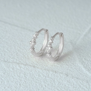 Macro detail of silver S925 heart earrings with white cubic zirconia on stone texture