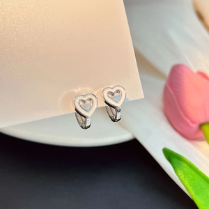 Gros plan de boucles d'oreilles argentées en forme de cœur creux sur carte
