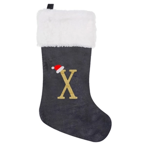 Detail of grey velvet Christmas stocking with golden glitter letter X and white faux fur cuff