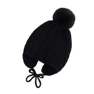 Detail of black cable knit baby winter hat with large faux fur pompom and earflaps