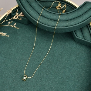 Detailed macro shot of K18 hallmark on the gold chain with a green zircon pendant
