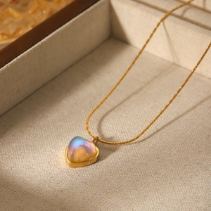 Élégant collier cœur en or 18k avec pierre de lune irisante sur plateau à bijoux