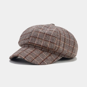 Detailed view of brown checked newsboy hat showing wool texture and octagonal stitching