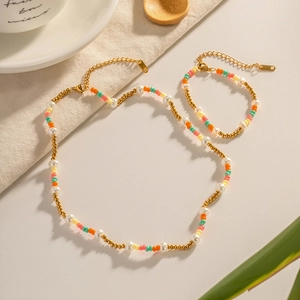 Colorful pearl and bead jewelry set with gold necklace and bracelet on beige background