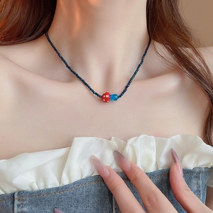 Close-up of a sweet mushroom pendant necklace with black beads and a red bow charm