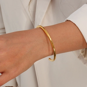 Detail view of a minimalist 18K gold-plated stainless steel open bangle on a model wrist