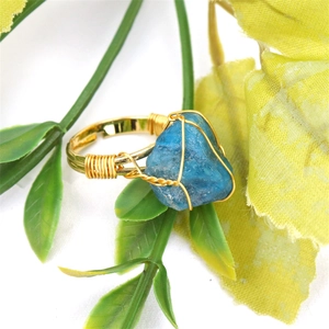 Macro view of blue raw gemstone ring with golden wire-wrapped handmade details
