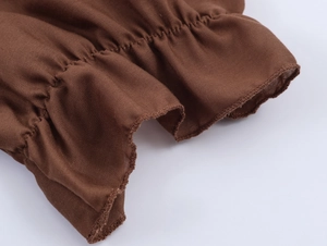 Détail macro des poignets plissés marrons avec bords volantés et coutures fines