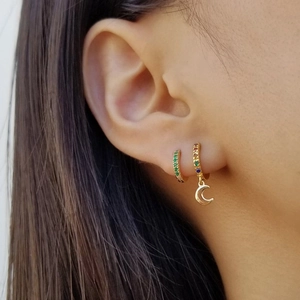 Detail of gold hoop earrings with green and colorful zircon stones and moon pendant