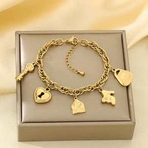 Detailed close-up of gold stainless steel charm bracelet with heart and key pendants