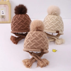 Close-up of knit baby earflap hats with pom-poms in brown, khaki, and cream colors