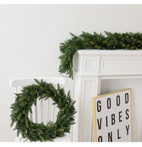 Macro detail of artificial green pine garland with warm white LED lights for holiday decor