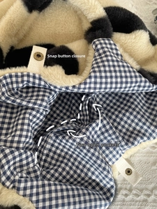 Detail of plush tote bag with snap button closure, checkered lining and dual inner pockets
