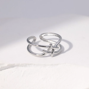 Detail view of double-layered silver stainless steel open ring on a white matte surface