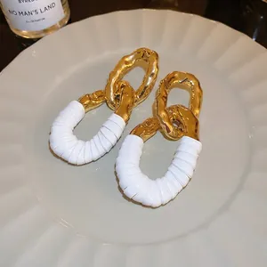 Boucles d'oreilles dorées torsadées avec détail en cuir blanc pour femmes élégantes