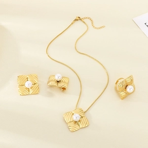 Detail of gold-plated square textured jewelry set with pearls on necklace and earrings