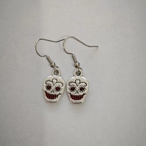 Macro shot of gothic skull earrings with red heart accents and silver finish hooks