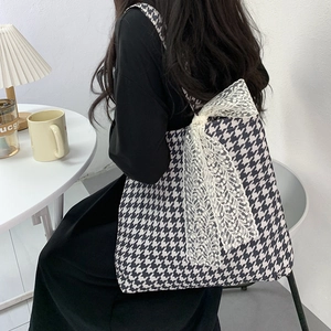 Houndstooth canvas tote bag with white lace bow detail shown on shoulder of a model