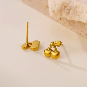 Polished gold cherry stud earrings shown on minimalist stone prop for detailed texture