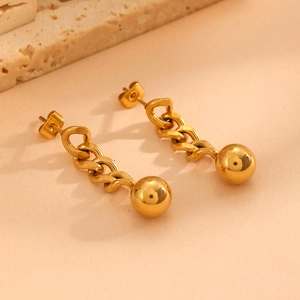Detailed close-up of gold chunky chain earrings with polished ball pendants on stone