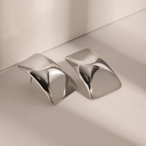 Detail of silver geometric square earrings with polished curved surface and modern style