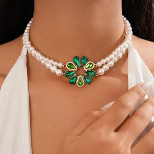 Detail of double-layer pearl necklace with emerald green gemstone flower pendant on neck