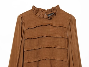 Detail of brown long sleeve top featuring smocked fabric and ruffled collar texture